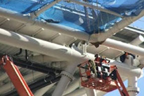 [image] Worker standing on a mobile elevating work platform while installing a safety net